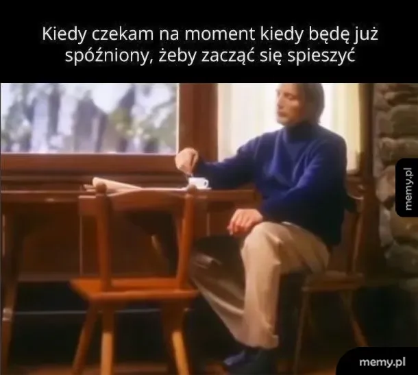 Mads Mikkelsen siedzi spokojnie przy stole i miesza kawę.